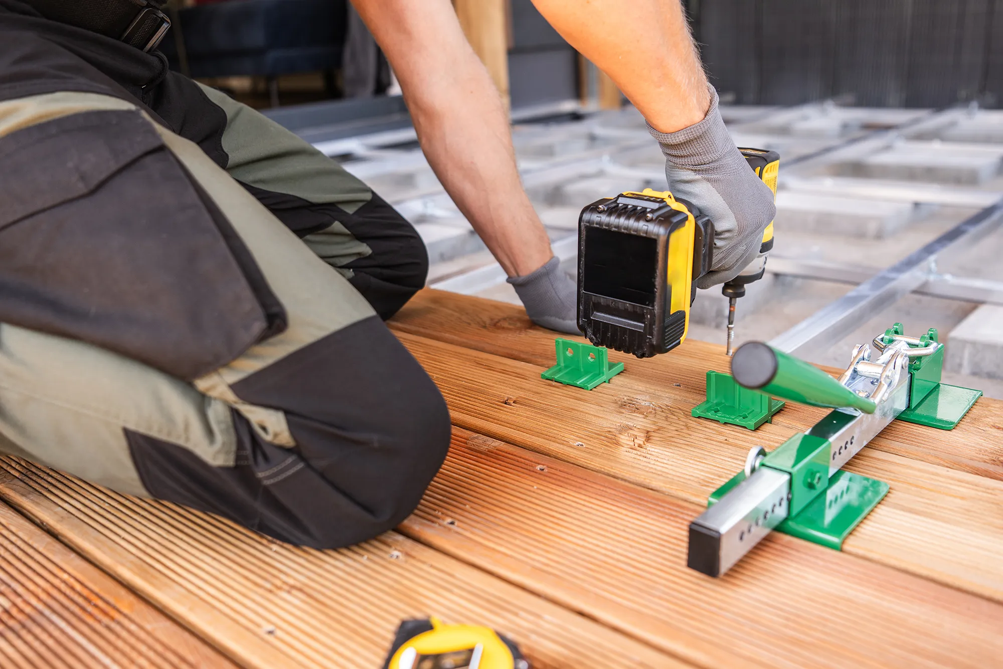 worker-assembling-wooden-deck Selection of engineered construction hardware for durable framing and structural safety.